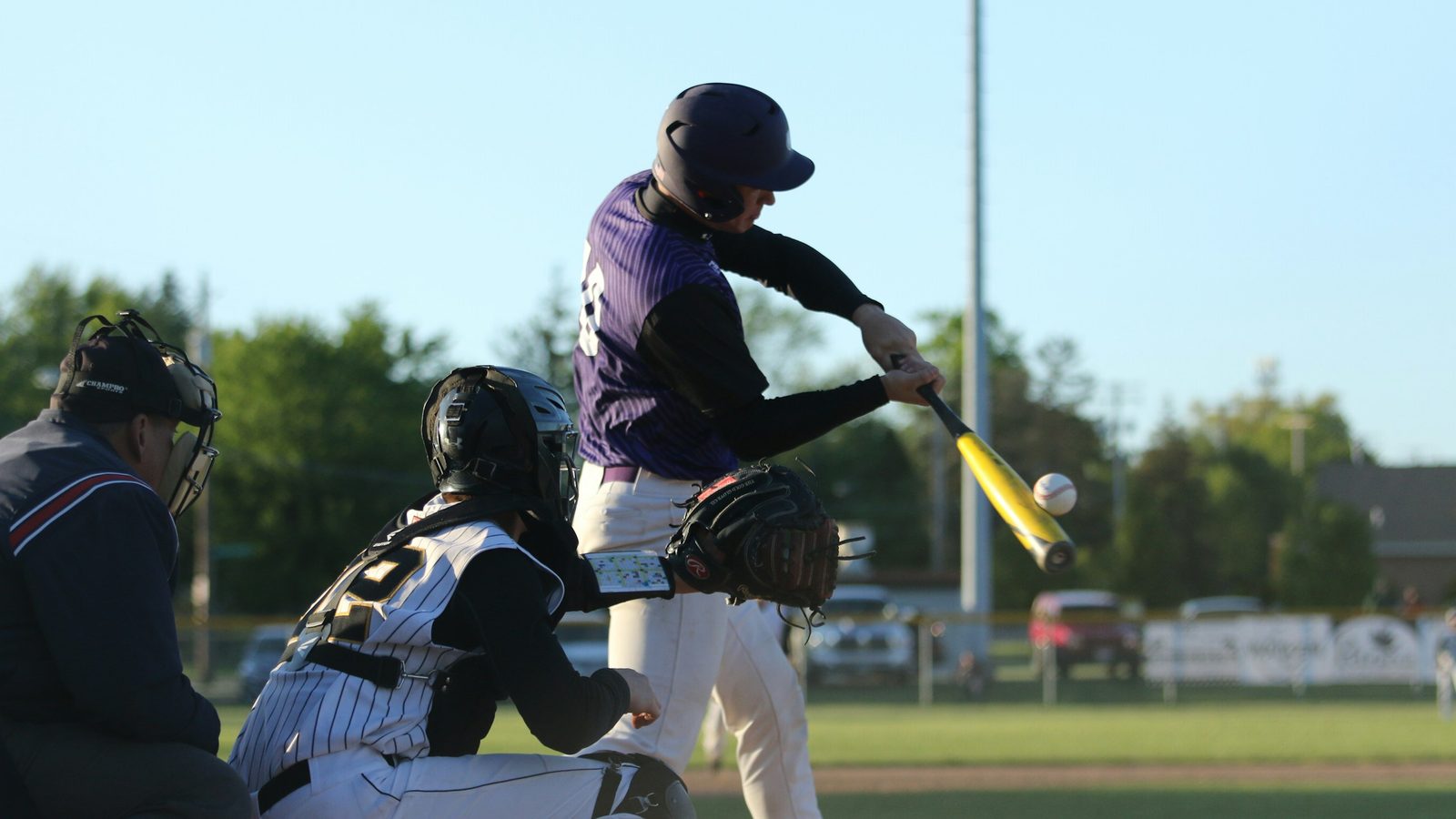 A high school hitter at contact, filmed from the side, with the ball on the barrel