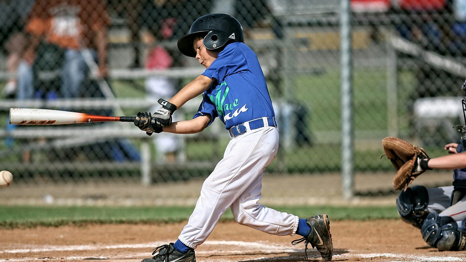 A little league hitter at contact, arms extended, weight moving onto the front side