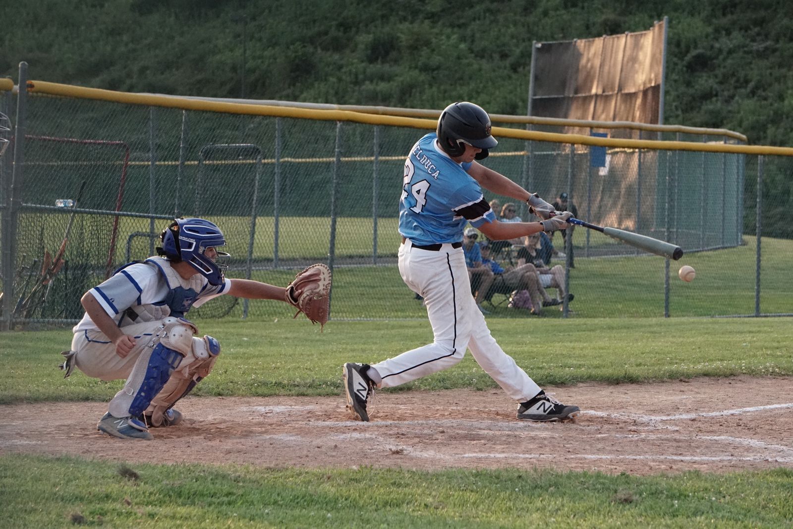 Youth hitter at contact in a game, hands inside the ball and the back foot turned toward the pitcher